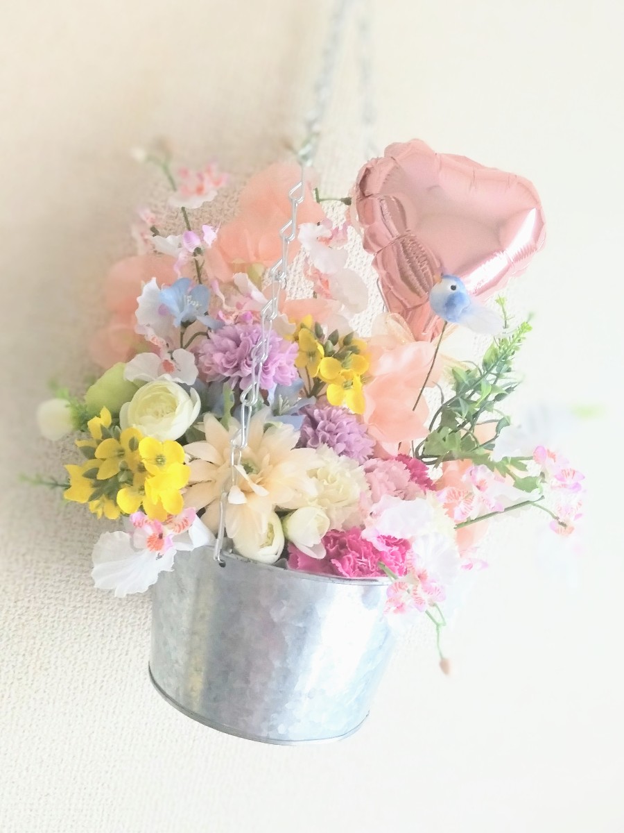 小鳥も囀る春の花々 母の日が近いので、カーネーションを下の方に少しと、ハート型のアルミ風船も入れて、いかにもギフト用品の様に作っていきました。
そして、旬の菜の花を入れ、青い小鳥のピックも入れ、春の花々をアレンジし、春の kiraymark フラワー GiftShop