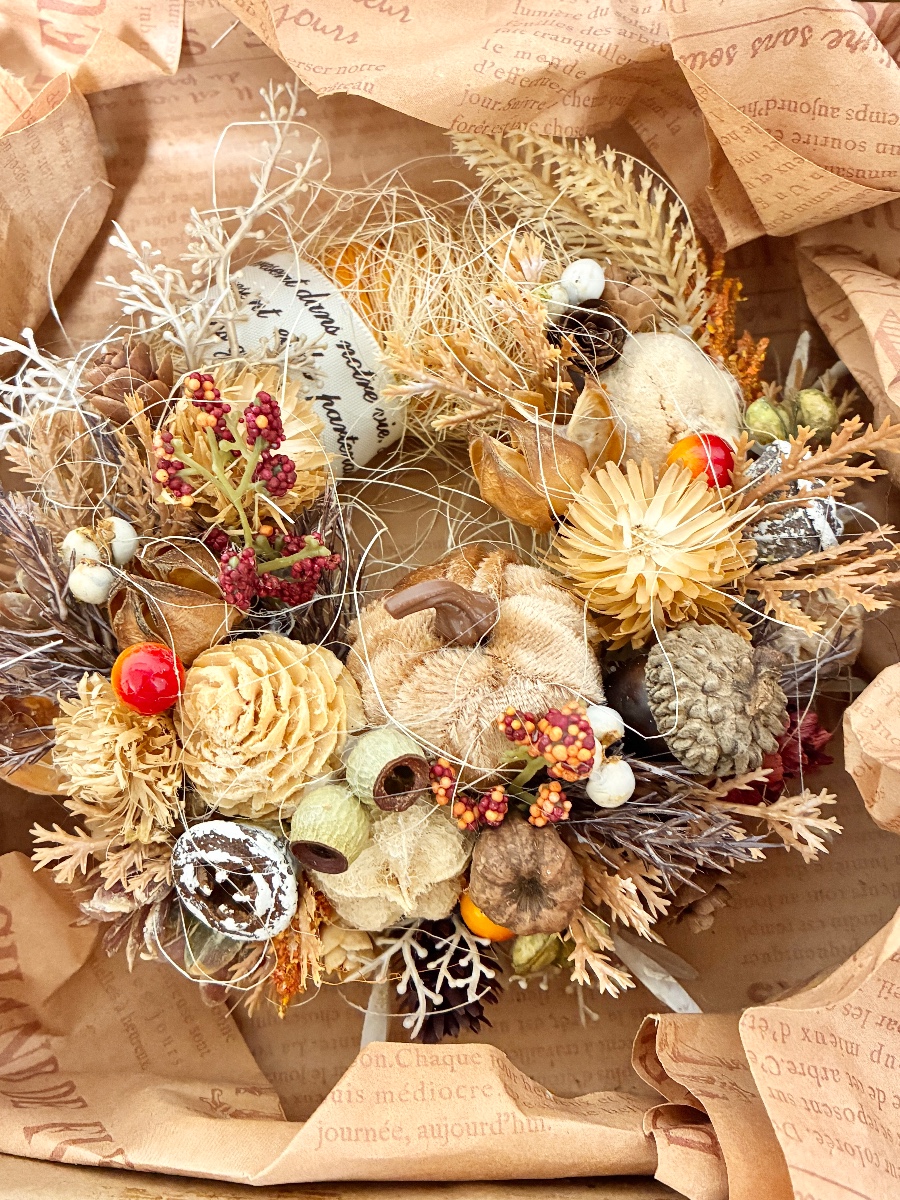 ドライフラワーのオータムリース スチロールベースにラフィアを巻いてかぼちゃや木の実などドライ花材を飾った こんもりかわいいナチュラルリースです。 tera