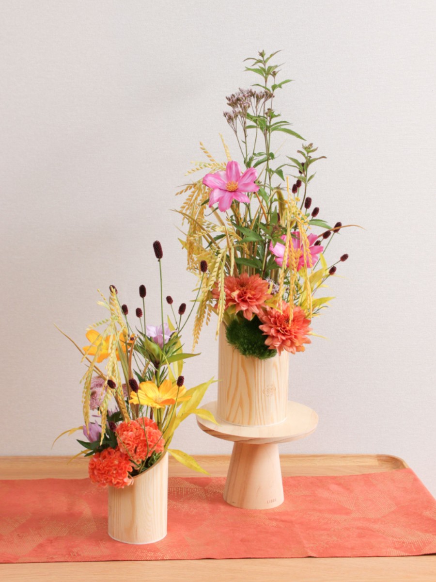 生花と造花のハイブリッドデザイン　秋花の月見アレンジ お月見の代表的な花材であるススキは、豊穣祈願の象徴である稲穂に似ていることから使われていました。
稲穂はお月見の時期にはまだ入手できない花材ですが、実り豊かな稲穂を再現したアーティフィシャルフラワーで 横浜ディスプレイミュージアム